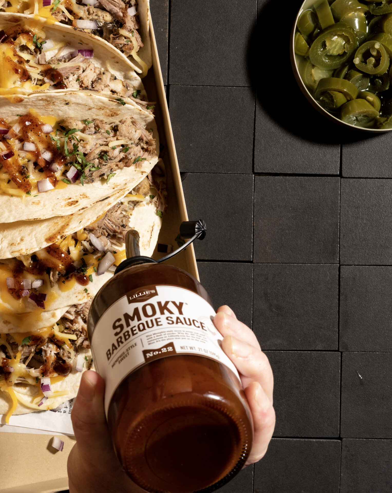 Schaal met taco's en hand met fles saus