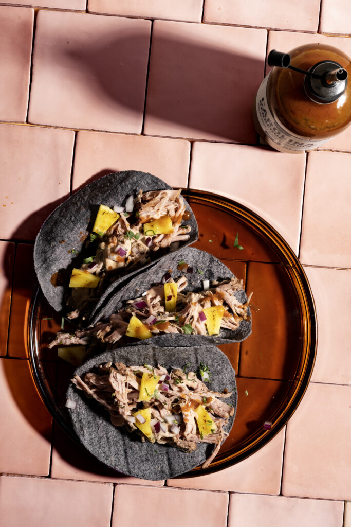 Bord met 3 taco's gemaakt van zwarte tortilla's en een fles saus